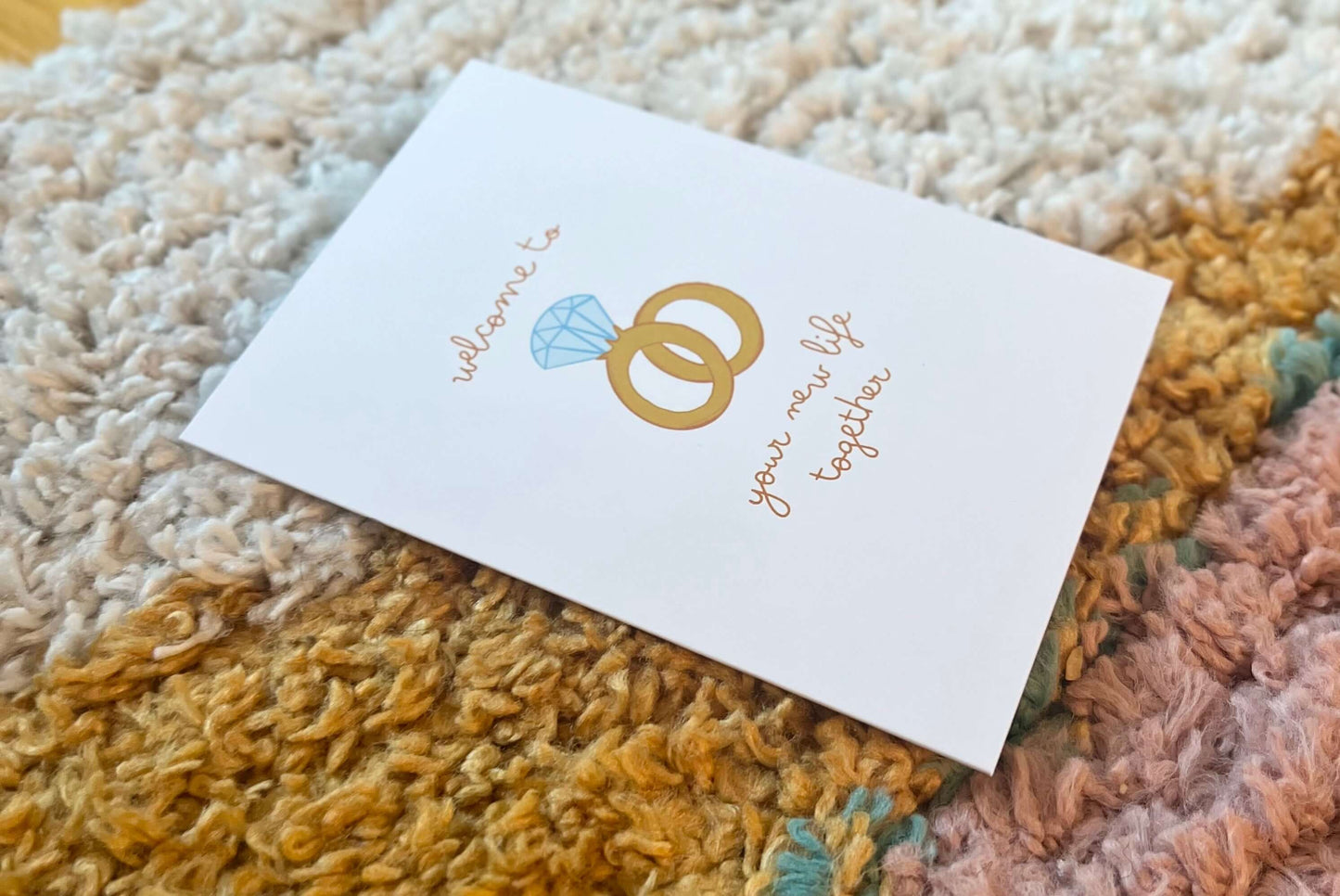 hand drawn greeting card with a diamond ring and wedding band that says welcome to your new life together.