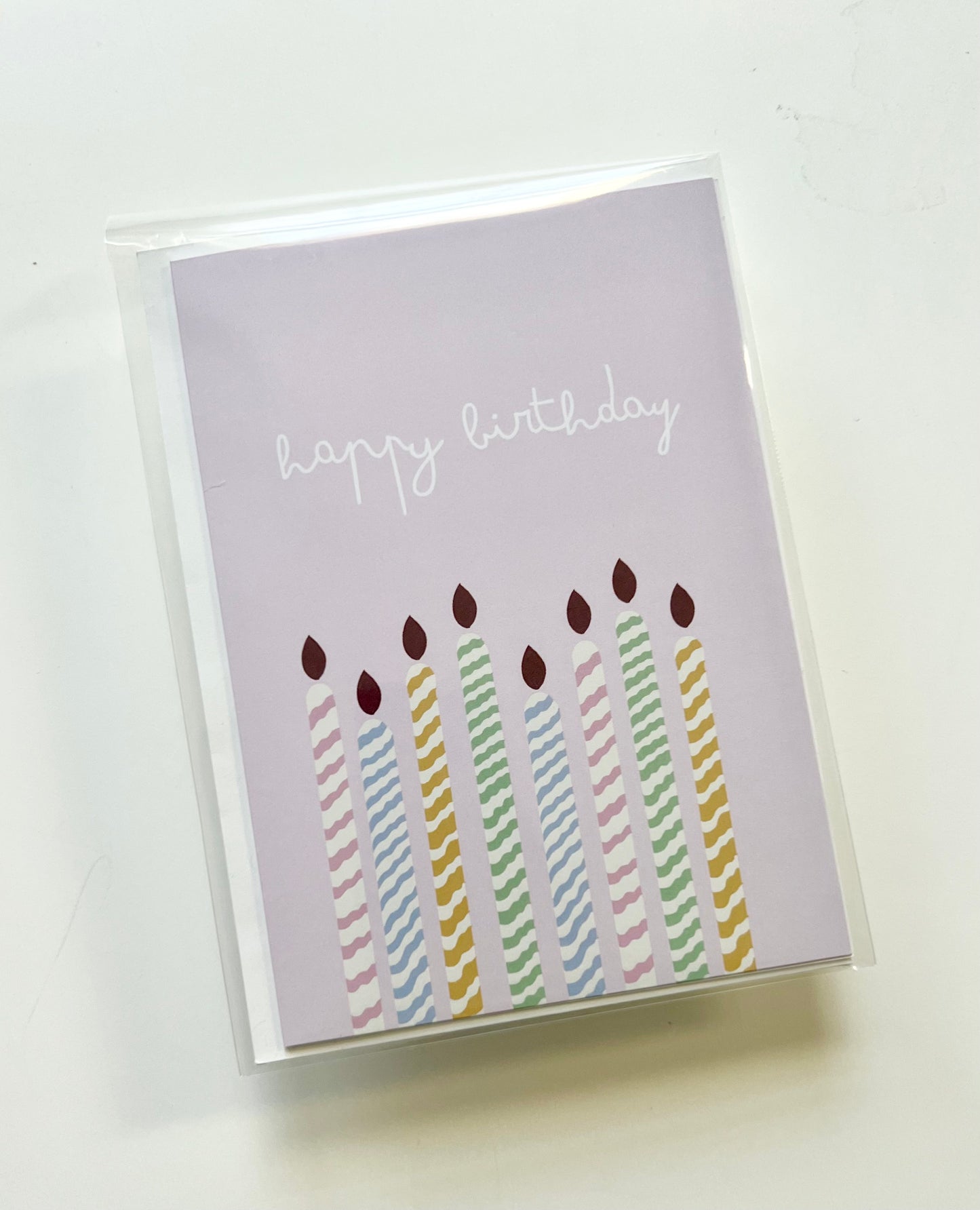 hand drawn purple greeting card with colorful candles that says happy birthday.