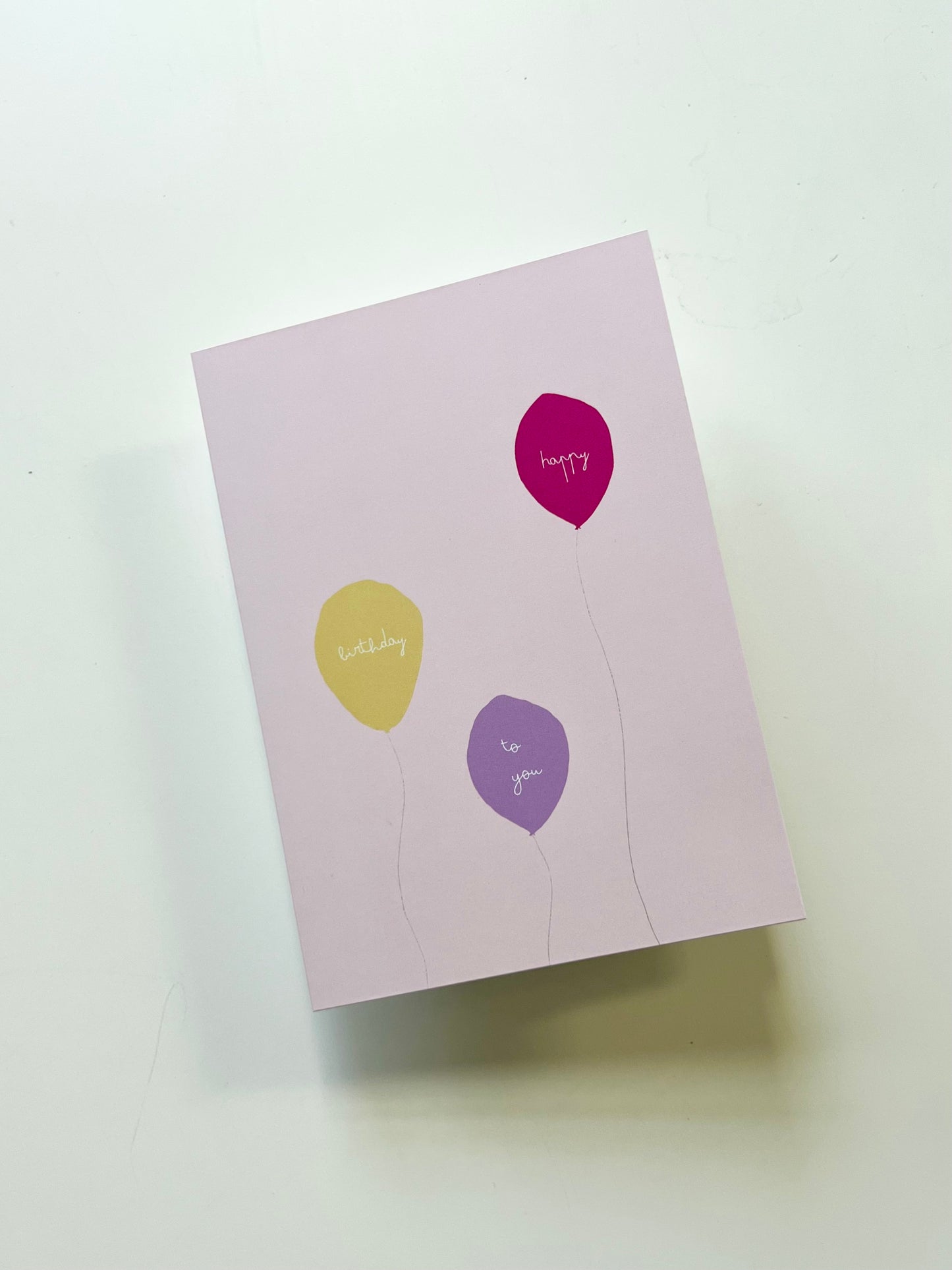 hand drawn pink greeting card with a yellow, purple, and pink ballon that says happy birthday to you.