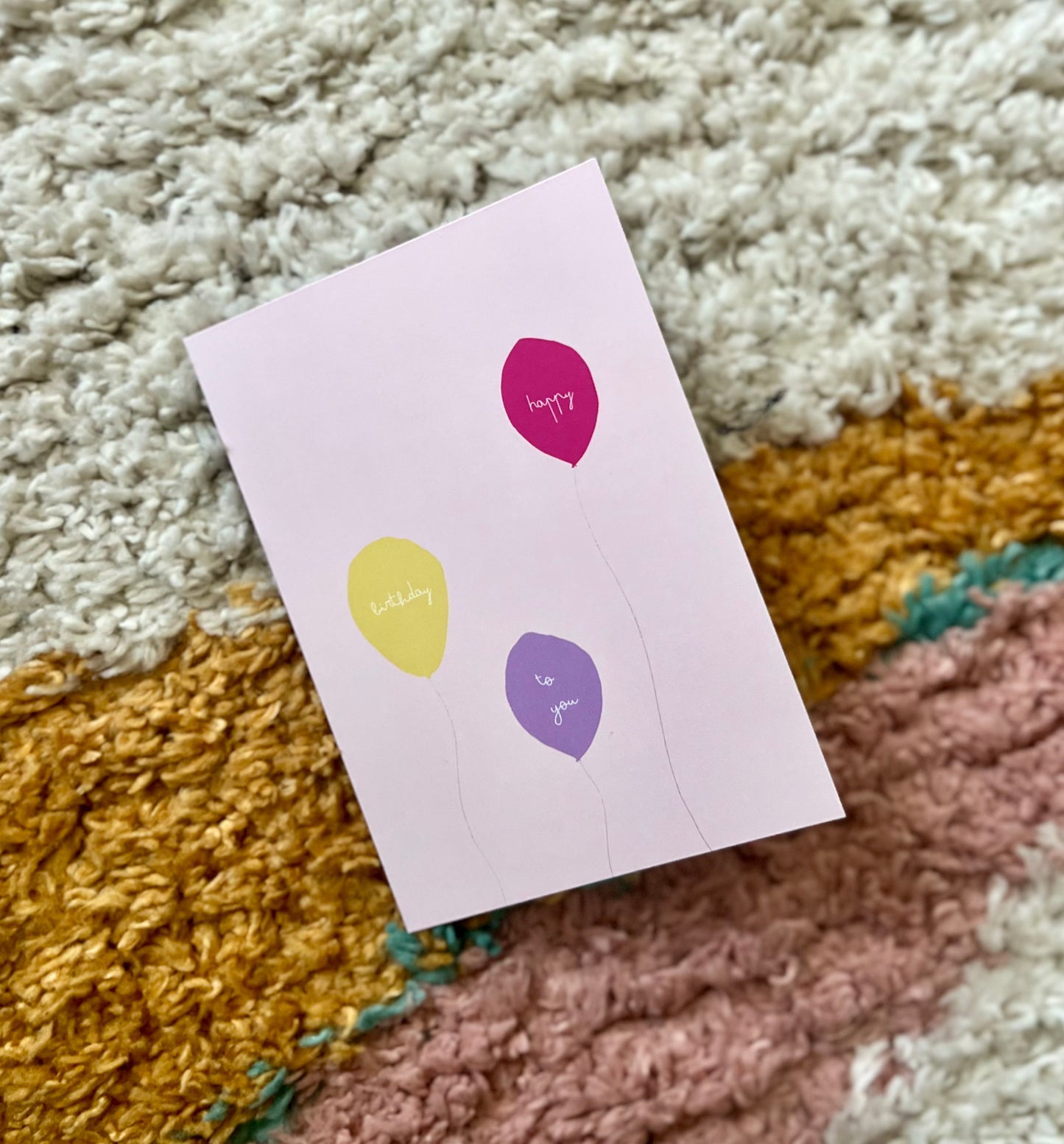 hand drawn pink greeting card with a yellow, purple, and pink ballon that says happy birthday to you.