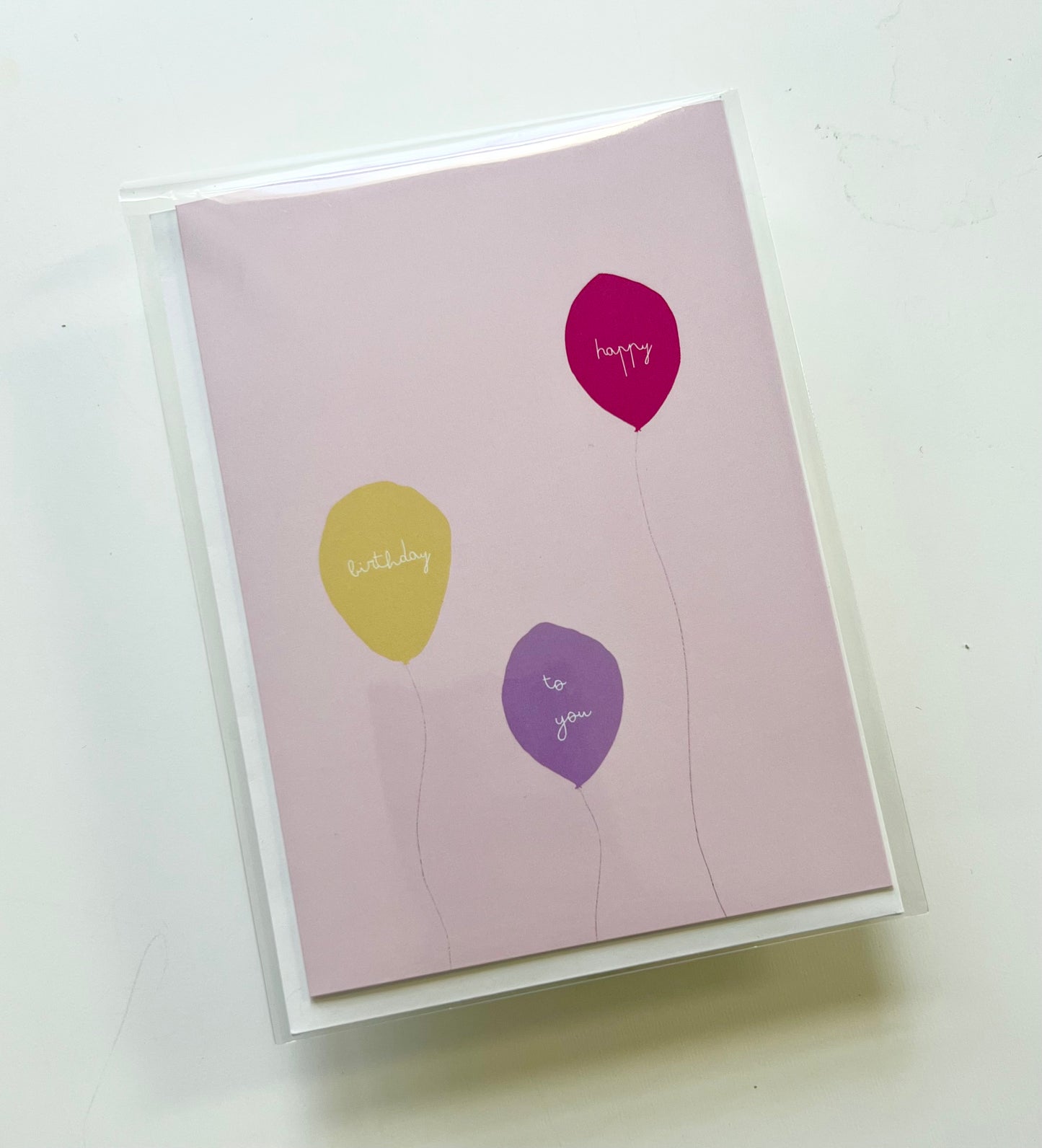 hand drawn pink greeting card with a yellow, purple, and pink ballon that says happy birthday to you.