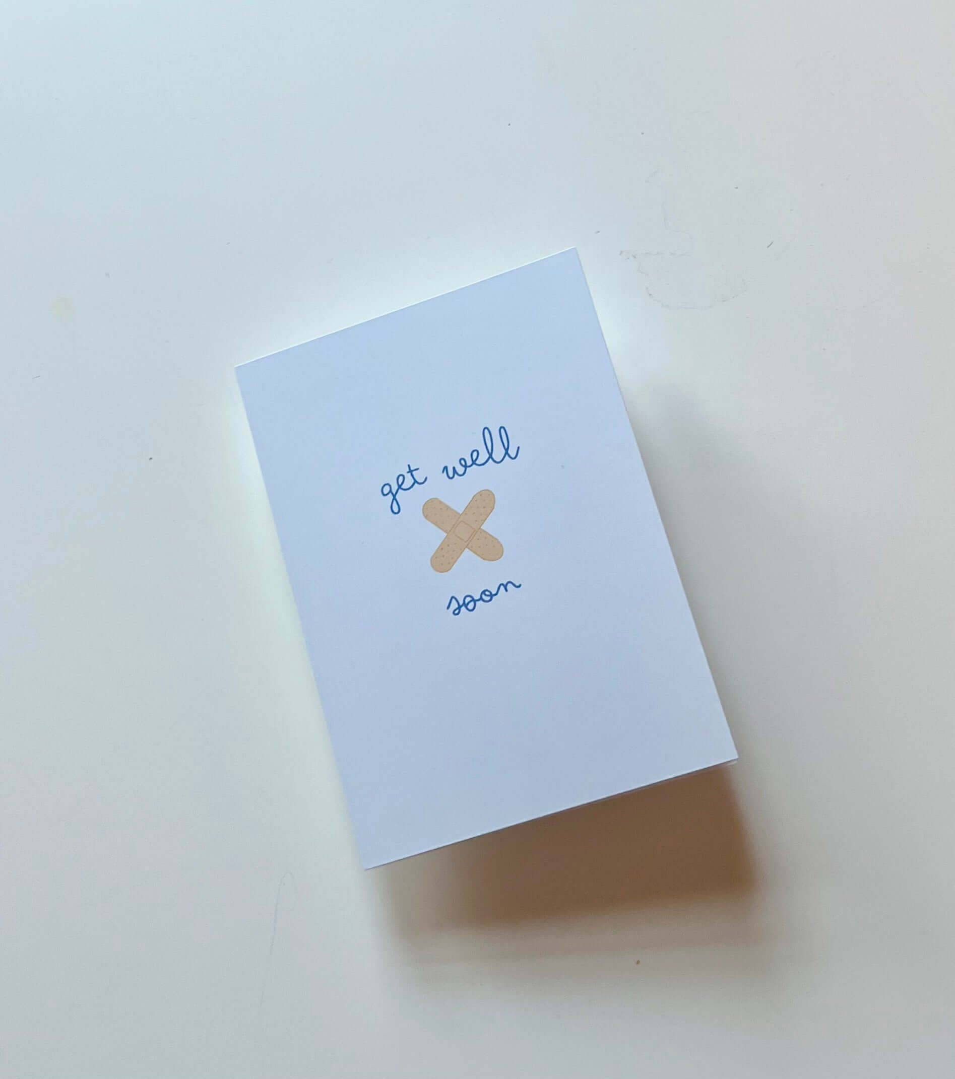 hand drawn blue get well soon greeting card with you crossed bandaids.