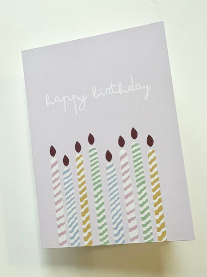 hand drawn purple greeting card with colorful candles that says happy birthday.