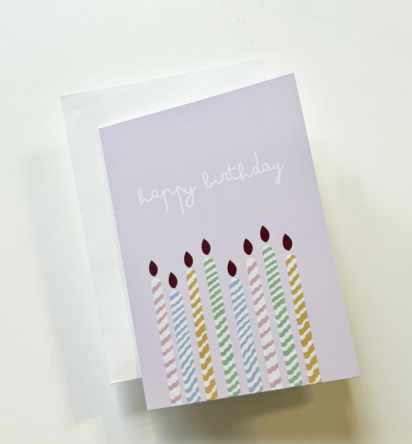 hand drawn purple greeting card with colorful candles that says happy birthday.