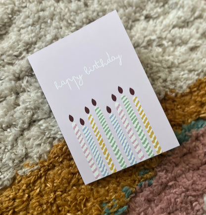 hand drawn purple greeting card with colorful candles that says happy birthday.