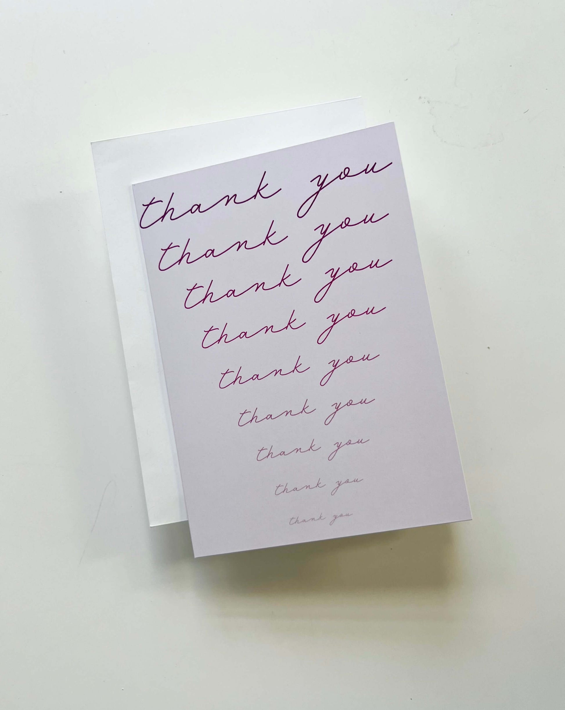 Hand drawn thank you card with cursive text on a pink background, packaged with a white envelope.