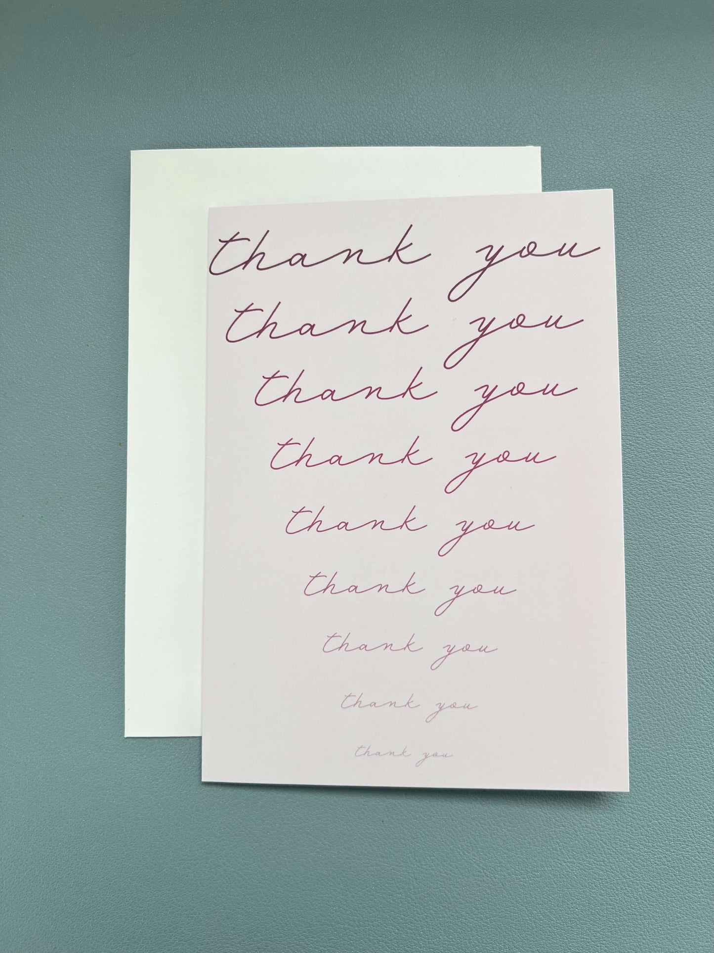 Fading pink thank you card with cursive text, blank inside, accompanied by a white envelope.