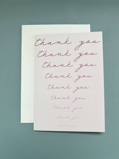 Fading pink thank you card with cursive text, blank inside, accompanied by a white envelope.