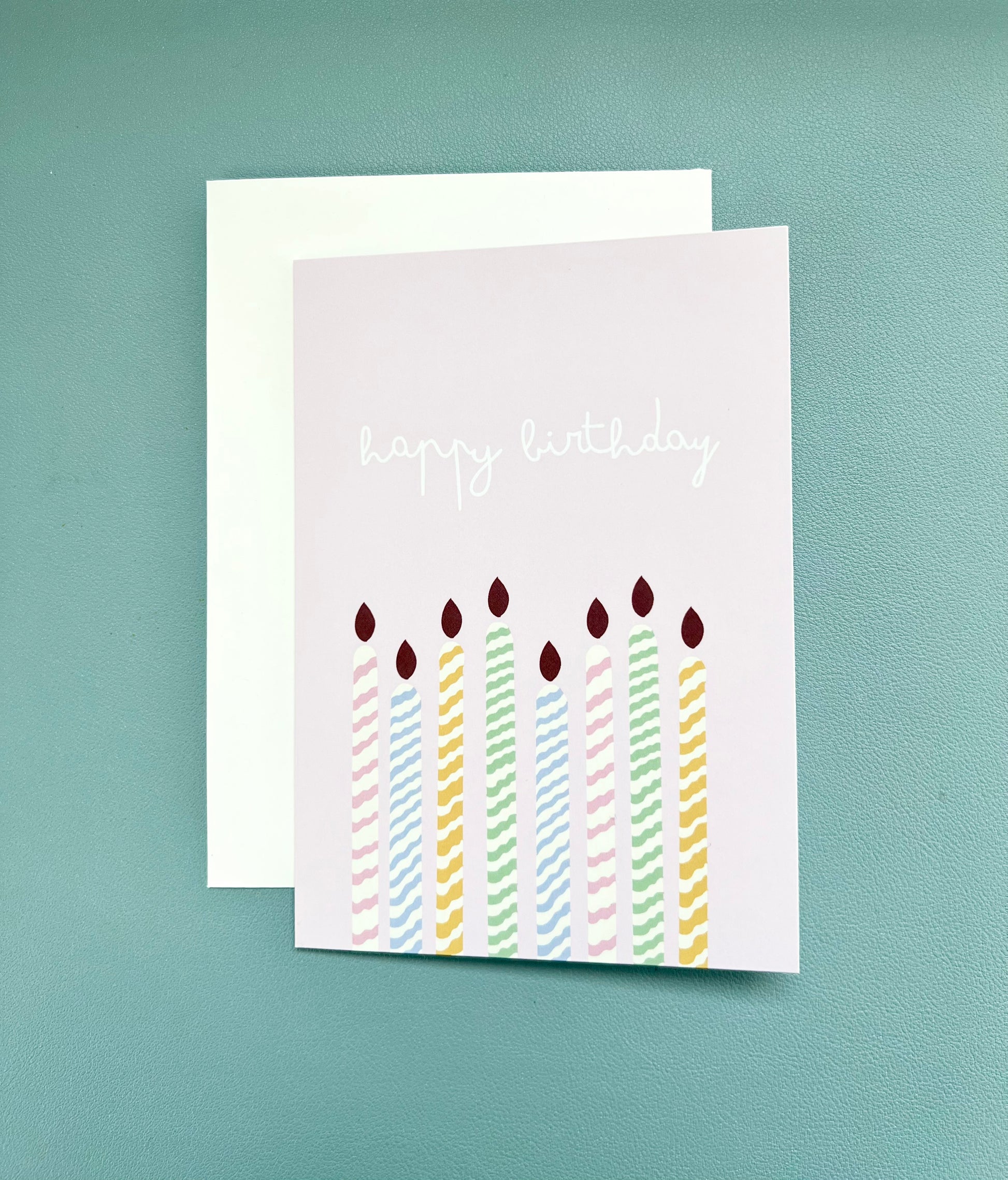 hand drawn purple greeting card with colorful candles that says happy birthday.