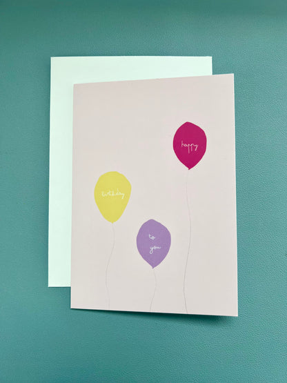 hand drawn pink greeting card with a yellow, purple, and pink ballon that says happy birthday to you.